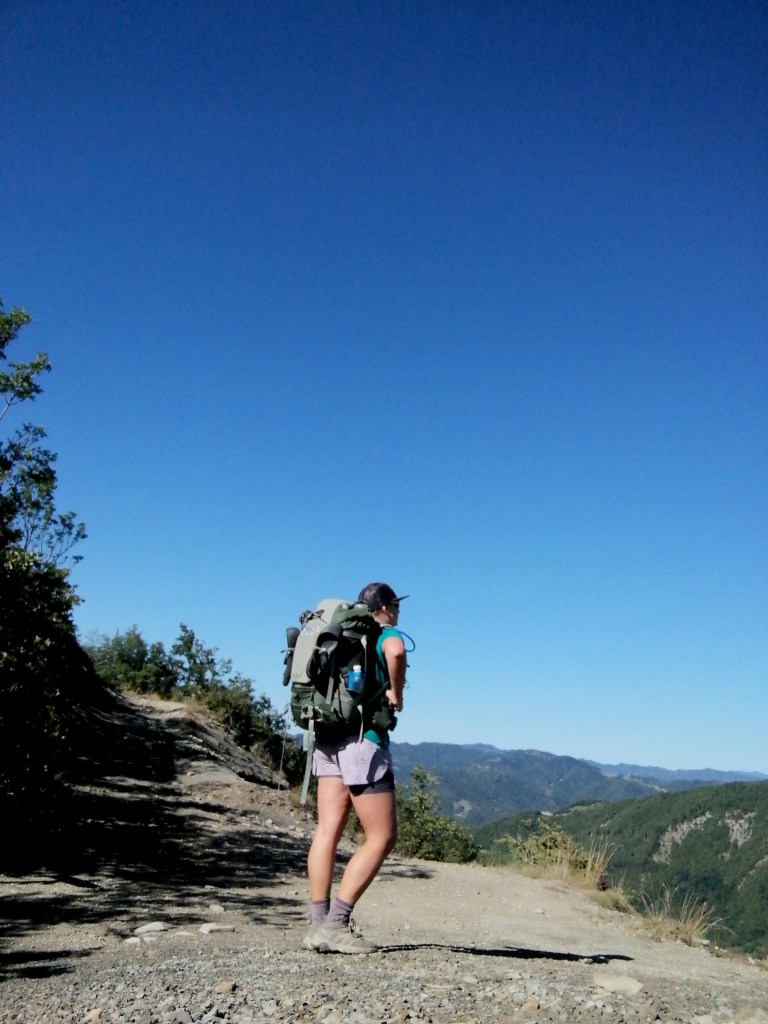 woman with backpack hiking out under blue skies