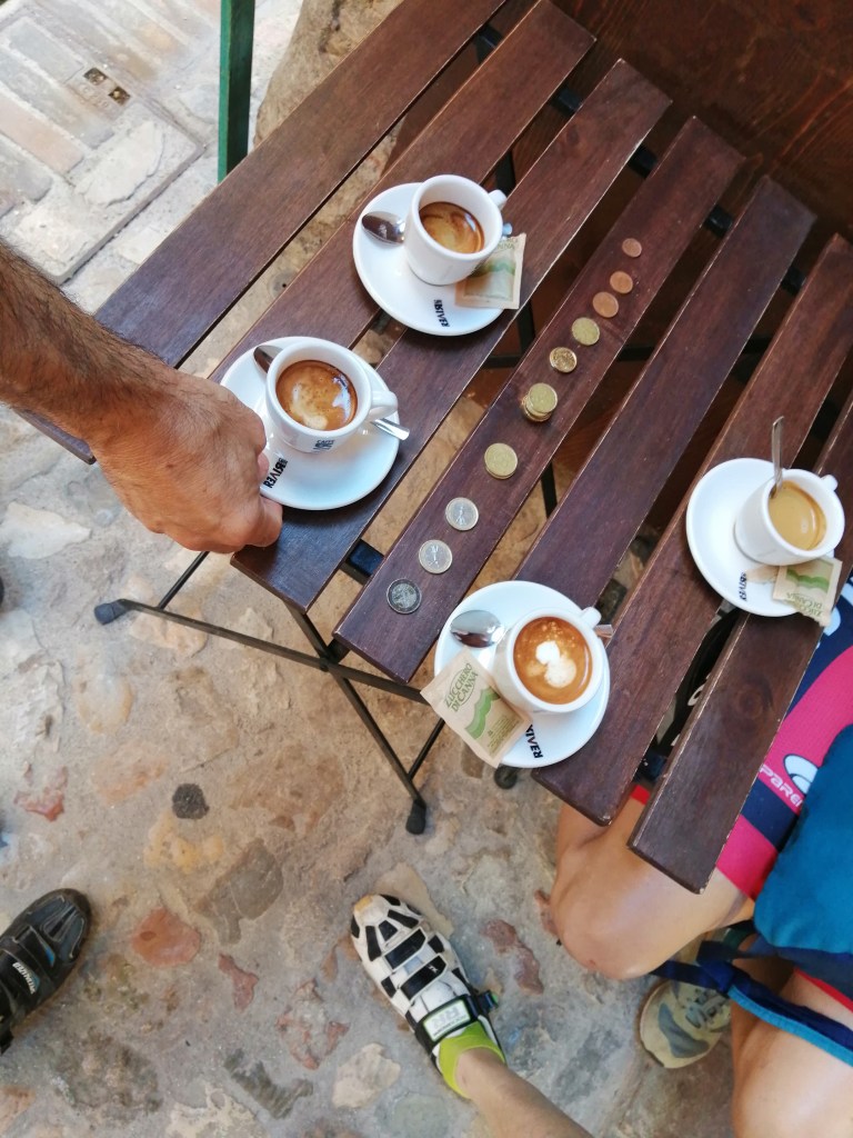 Four coffees, stacks of coins to pay for them all and underneath, somebody's bike shoes.